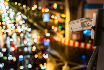 Security camera overlooking city traffic with bokeh lights at night. Blurred urban background