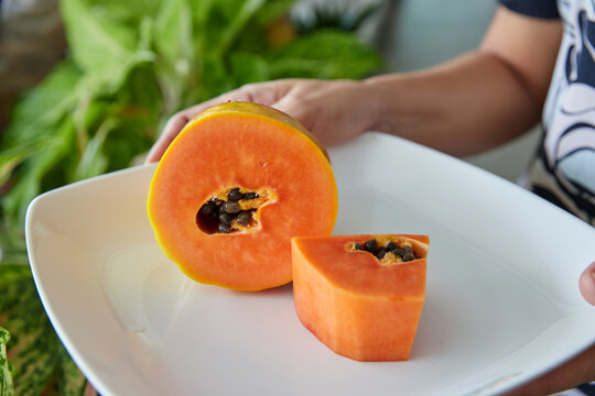 Cropped hand holding ripe papaya in plate
