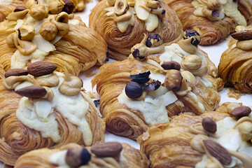 Group of fresh baked croissants, with topping of butter cream, caramel and roasted hazelnuts