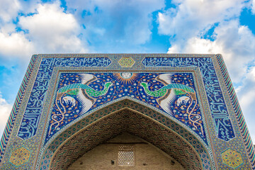 Colorful Portal of the Nadir Devanbegi Madrasah in Bukhara, Uzbekistan. Mosaic of the mythical Huma birds with Sun among floral pattern on the portal of Nadir Divan-Begi Madrasa in Bukhara, Uzbekistan