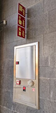Instalaci&oacute;n de seguridad contra incendios, con se&ntilde;ales, armario de metal para manguera y extintor y pulsador y luz de alarma, en muro de centro comercial 