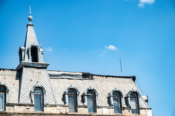 An ornate historic European building from the early 20th century with a detailed mansard roof...