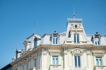 An ornate historic European building from the early 20th century with a detailed mansard roof against a clear sky