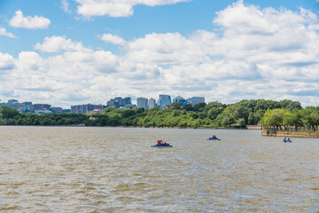 A distant view of paddle boats on the Tidal Basin with Arlington’s skyline in the background.