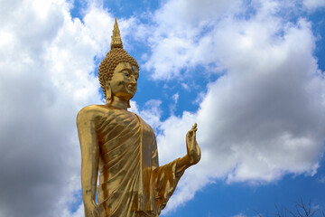 Obraz premium Side view of Golden Buddha statue at Wat phuttha prommayan, Chachoengsao Province Thailand. Blue sky background with copy space