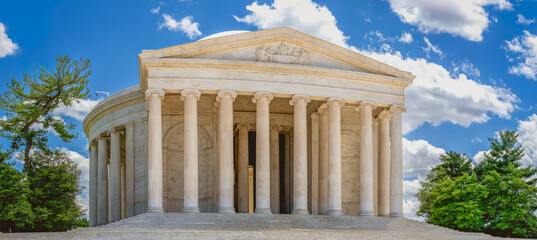 The neoclassical Jefferson Memorial stands prominently with its white marble columns against a backdrop of clouds and trees.