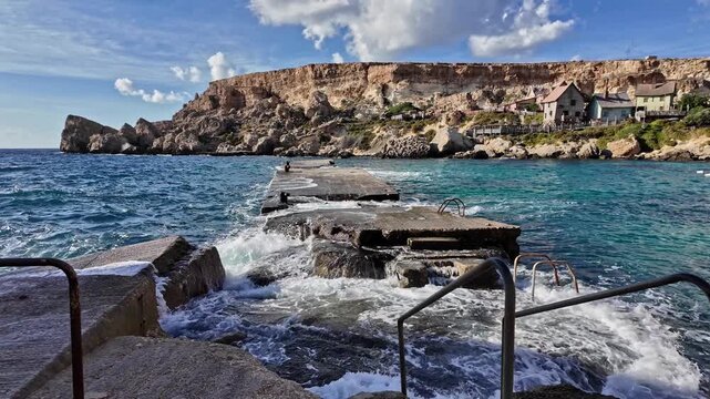 Wavees breaking on the shore oposite Popeye Village, Malta. High quality 4k footage