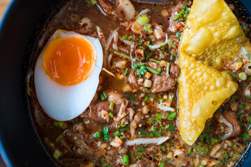 Delicious Spicy Tom Yum Noodle Soup topped with eggs and dumplings