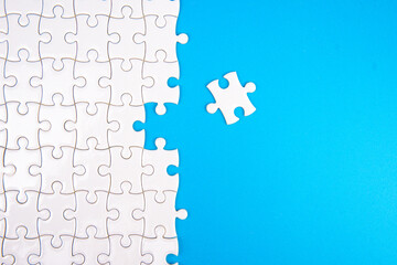 White puzzle with one missing piece on bright blue background. Concept of problem solving, teamwork, connection, solution, completion, and business strategy in minimal studio setup.