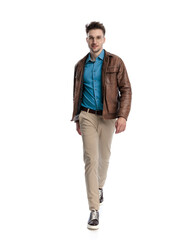 handsome young man in brown leather jacket walking and smiling