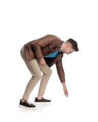 Obraz premium casual young man leaning forward and touching the ground while smiling