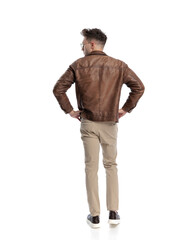 rear view of casual young man with glasses holding hands on hips