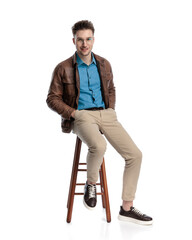 happy casual man with glasses holding hands in pockets sitting
