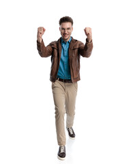 proud young man holding fists up and celebrating victory while walking