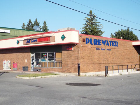 Nepean, ON, Canada, June 20, 2025: A single-story commercial building which houses two businesses: a "Bells Corner Kwik Mart" and "PUREWATER Total Home Leisure" at 2072 Robertson Road.
