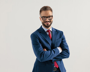 confident young businessman in navy blue suit crossing arms and smiling