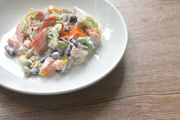 imitation crab stick with corn and garden pea couple cabbage vegetable topping shrimp egg salad dressing cream sauce on plate