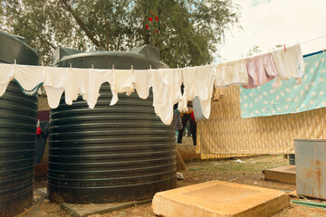 View of assorted clothes on a clothesline amidst water tanks behind apartments.