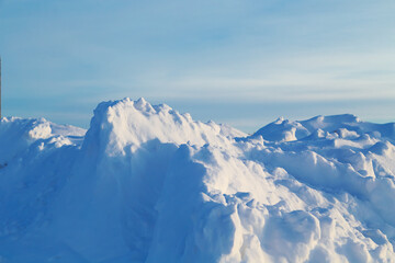 A huge pile of snow against a clear winter sunset sky.