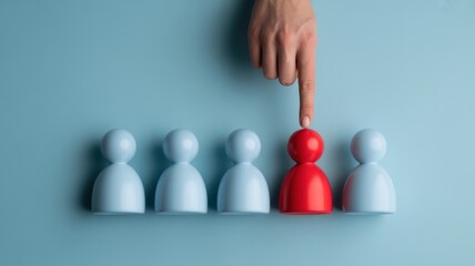 Hand selecting a red figure from a row of blue ones, symbolizing choice, individuality, and standing out from the crowd on blue background