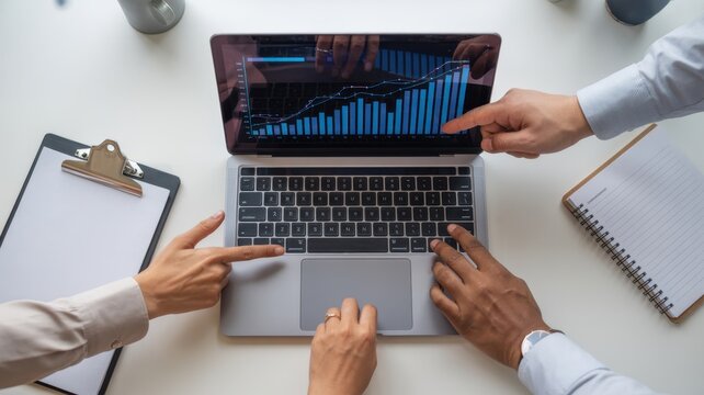 Collaborative analysis of stock market data on laptop with hands pointing at charts, representing teamwork, investment strategy, and financial planning - Powered by Adobe
