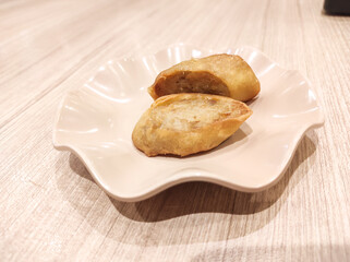 A top-table shot of a plate of chicken egg rolls. This Japanese meat dish is served on a wooden table.