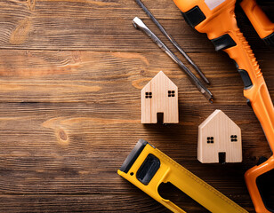 Wooden Mini Houses and Tools on Rustic Wooden Background