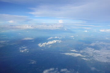 Beautiful white clouds drifting peacefully in the blue sky as seen from above or Layers of soft clouds stretching across the sky during a daytime flight.