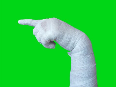Mummy hands wrapped in a bandage. pointing hand gesture. Index finger pointing to something, attention, direction. isolated on a green background. Halloween concept.