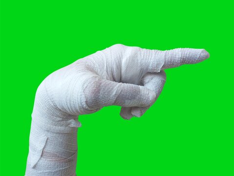 Mummy hands wrapped in a bandage. pointing hand gesture. Index finger pointing to something, attention, direction. isolated on a green background. Halloween concept.
