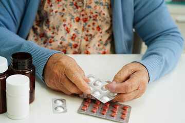 Asian elderly woman holding pill drug with water in glass, strong healthy medical.