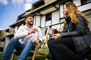 Young couple relaxing on loungers in front of hotel in autumn