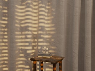 Symmetric product display table with book, candle shadow on sheer curtain.