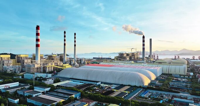 Aerial shot of a modern thermal power station with large smokestacks on the coast. Industrial energy generation background.