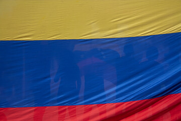 A crowd seen through the transparency of a Venezuelan flag. A symbol of unity and civic expression.