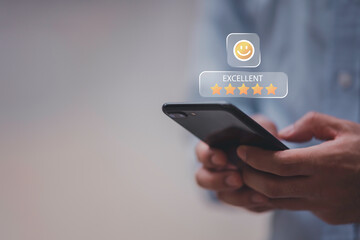 Businessman using smartphone to give five-star positive review with smiley face icon, Customers give 5-star reviews,symbolizing excellent customer feedback, and user satisfaction in digital service.