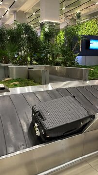 suitcases on luggage conveyor belt at baggage claim at Soekarno Hatta International Airport arrival area. the staff help to organize every luggage drop on the machine so it is not stuck with others