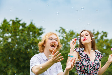 Couple blowing soap bubbles, having fun