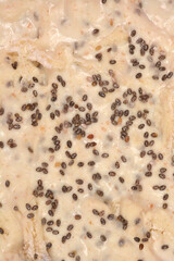 A macro close-up captures the raw bread dough surface generously dotted and covered with dark chia seeds