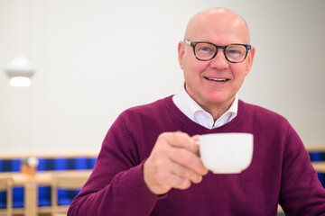 Portrait of a smiling senior man holding a cup of coffee