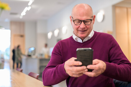 Portrait of a senior man using a mobile phone in a cafe - Powered by Adobe