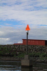 minimalist coastal scene with bright orange navigation sign and soft cloudy sky