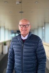 Portrait of a smiling senior Scandinavian man wearing eyeglasses in an airport corridor