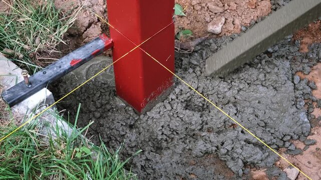 The worker is tamping a poured concrete. Compaction of the cement mixture. Pouring wet concrete from a mixer truck into a pit with pillar. Foundational work. Building industry. High quality 4k footage