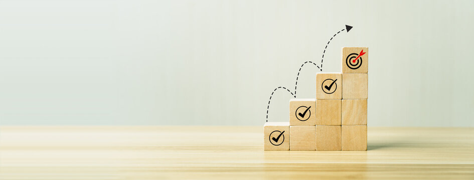 Goal achievement and business success concept with wooden block steps showing checklist icons leading to target dartboard, symbolizing strategy, planning, progress, and successful performance growth