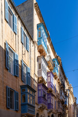 Obraz premium Vibrant Blue and Purple Maltese Balconies on Stone Building in Sunlight