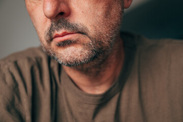 Closeup of mature adult man with stubble and serious expression, cropped face detail, thoughtful...