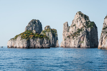 Naklejka premium Capri, Italy - 04.29.2025: Panoramic view from the sea of ​​the faraglioni limestone cliffs in the Tyrrhenian Sea near the island of Capri.