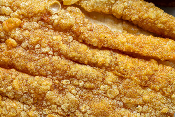Close-up of crispy pork texture,Close-up of crispy golden pork cracklings showcasing their textured surface. Perfect for food lovers, culinary enthusiasts, and snack aficionados
