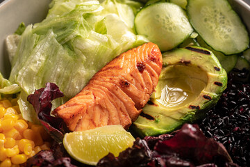 Closeup on healthy poke bowl with salmon, avocado, cucumber and vegetables